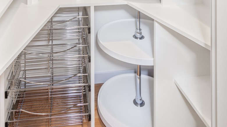 A pantry is fitted with organizing shelves, racks, and a tower of lazy Susans in the corner