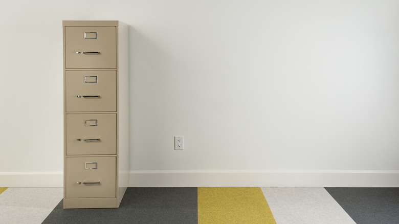 File cabinet against wall on striped carpet