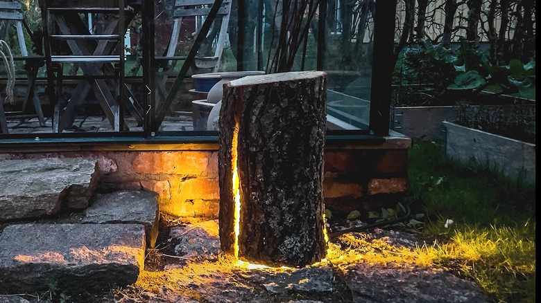 A tree stump cut open and turned into an outdoor lamp on someone's outdoor patio.