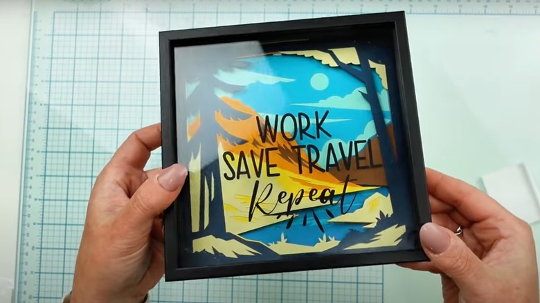 DIY shadow box piggy bank with words "Work, Save, Travel, Repeat" on it