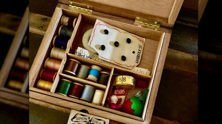 Shadow box filled with sewing tools and thread