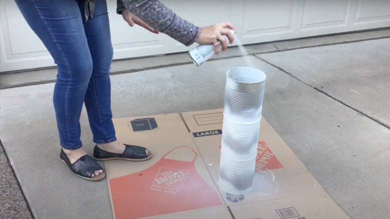 Someone spray painting a stack of empty coffee containers