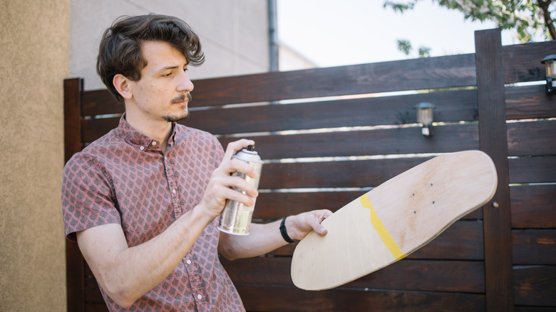 man spray painting skateboard