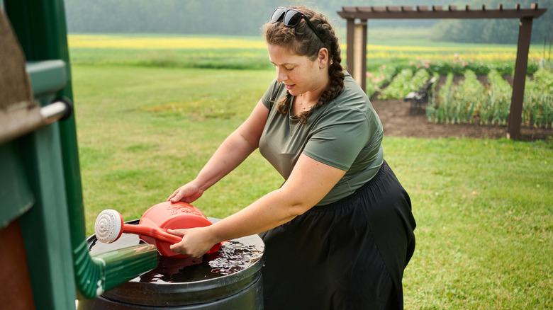 woman collecting water from barrel