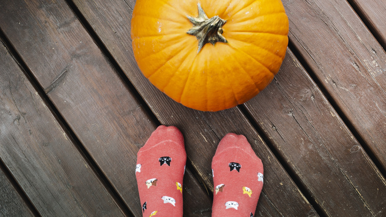 Socked feet near a pumpkin