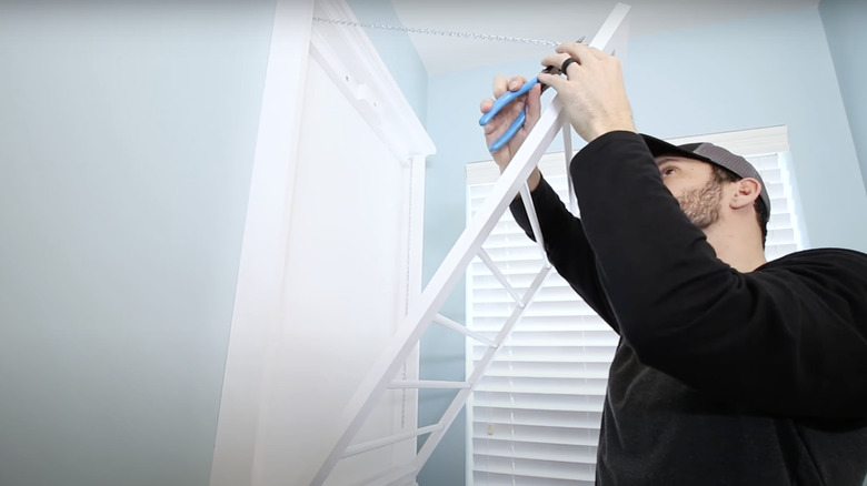 man attaching chains to crib drying rack 