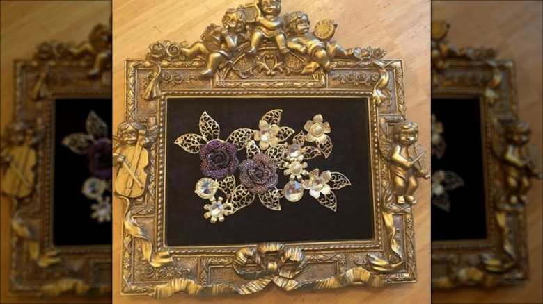 Ornate gold frame with brooch art on black background