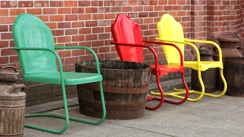 green, red, and yellow metal chair next to a brick wall