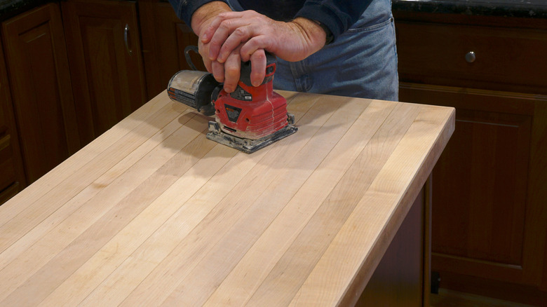 man sanding wood kitchen countertop