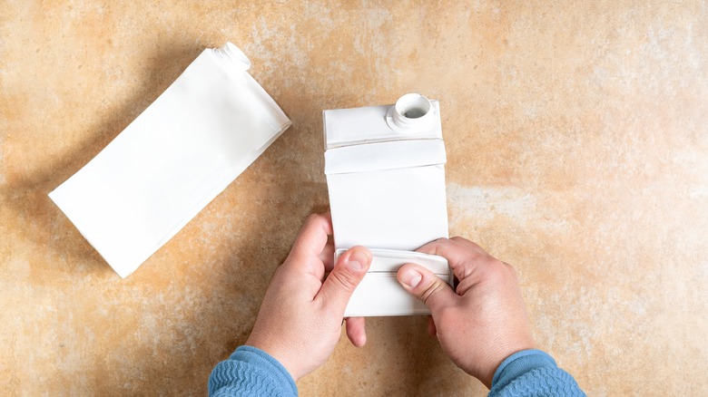 person folding milk carton