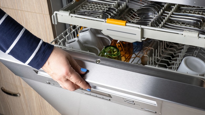 woman opens dishwasher door