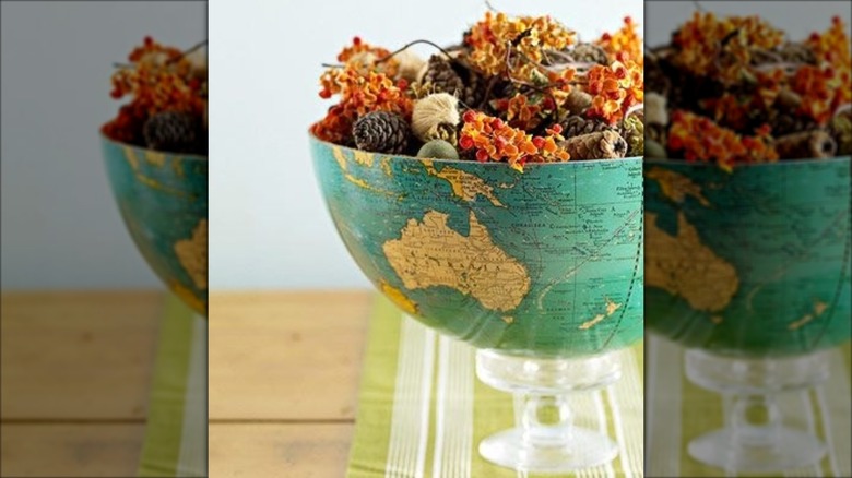 A globe repurposed into a bowl for dried flowers