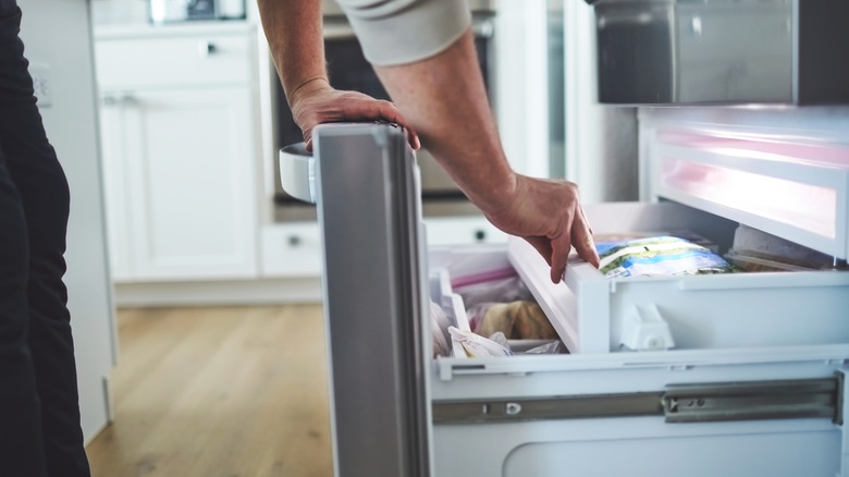 Arm of male opening a freezer drawer