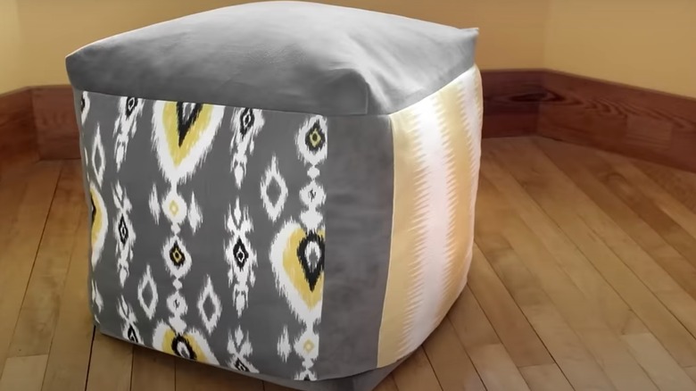 Patterned gray and yellow ottoman on wood floor