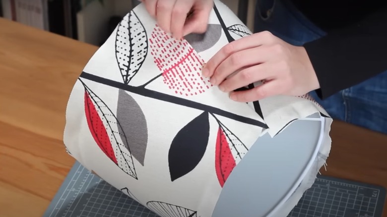 Person installing patterned fabric on lampshade