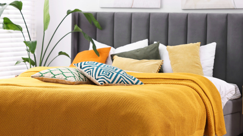 A variety of colored and patterned throw pillows on a bed