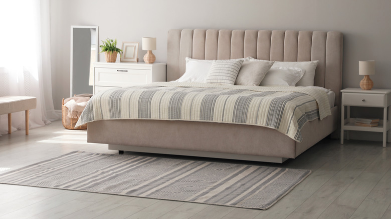 Thin grey striped rug at the foot of a bed