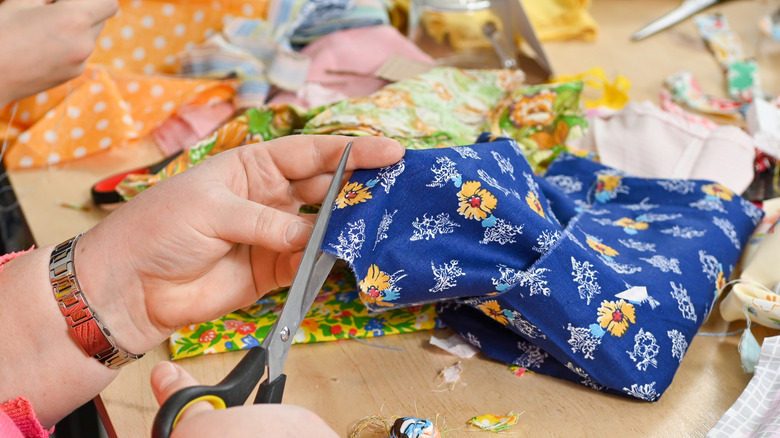 Person cutting fabric with scissors.