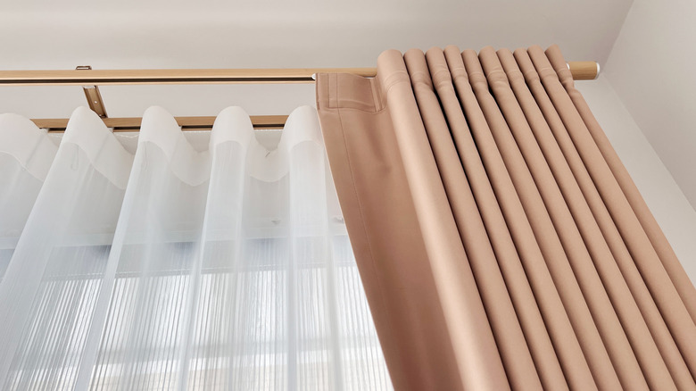 Upwards view of salmon colored curtains and sheer white curtains on a window