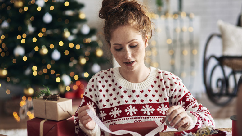 Woman creating Christmas crafts in home with Christmas tree behind