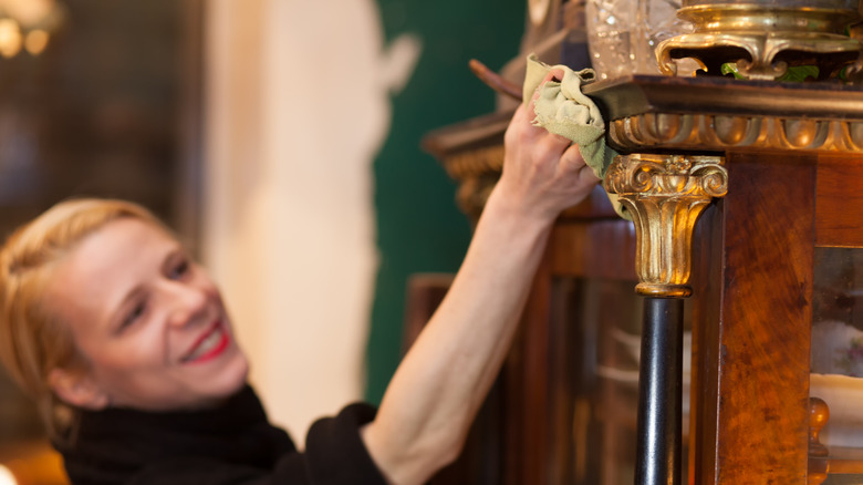 A person cleaning a piece of antique furniture with a cloth