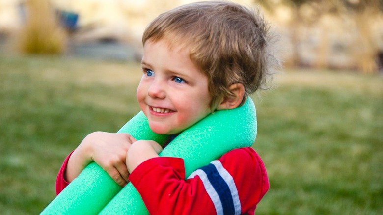 Little boy with pool noodle