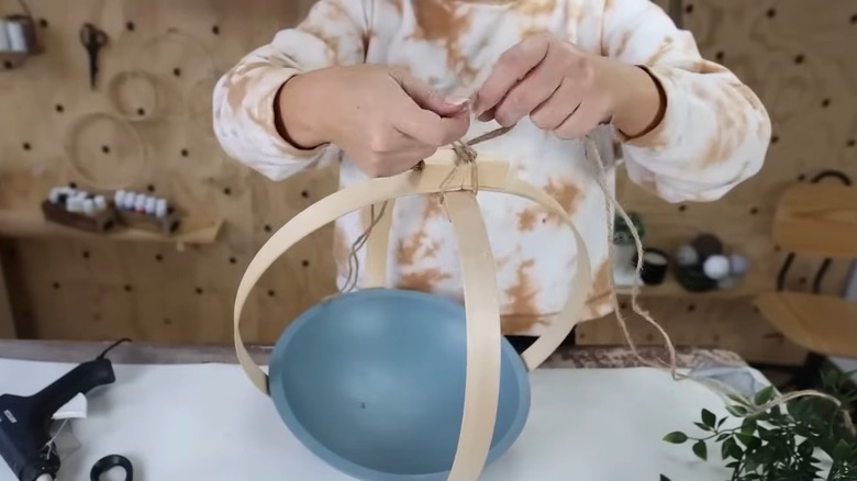 Woman tying twine to the top of DIY hanging planter