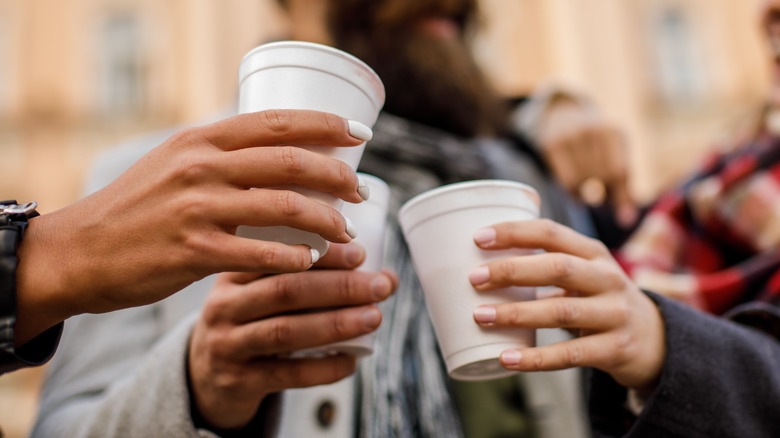 Hands holding white used styrofoam cups