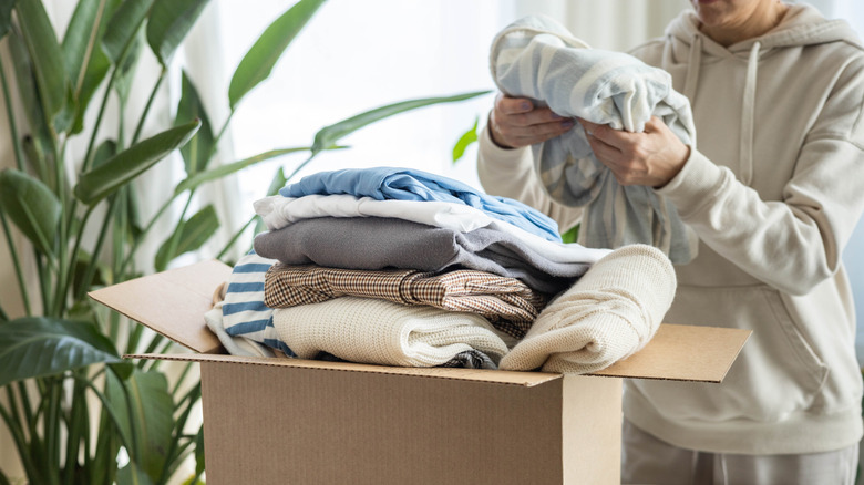 A woman packs clothing into a box.