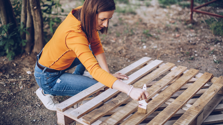 woman painting wooden palette 