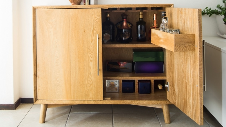 A wooden cabinet with wine bottles and compartments.