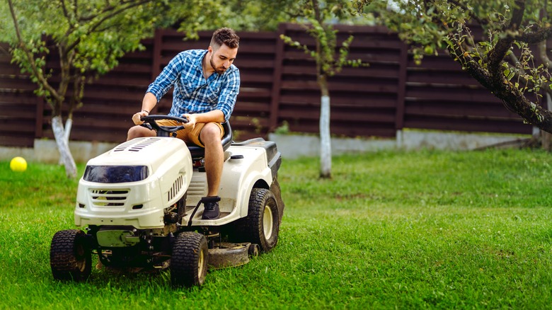 Man rides sitting lawn mower