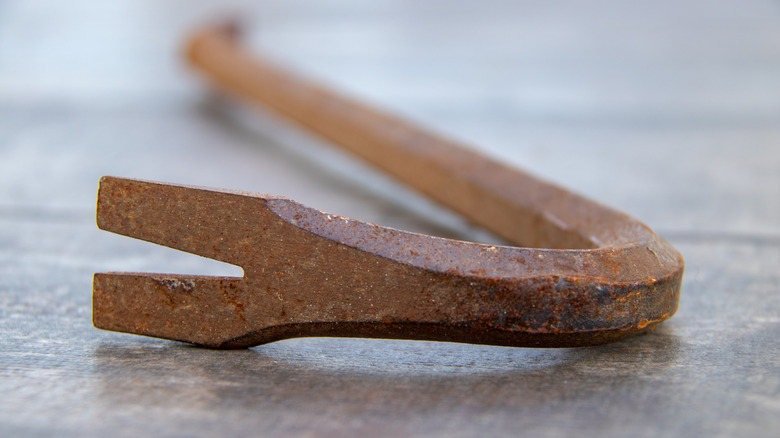 A close up of a rusty crowbar on a flat surface