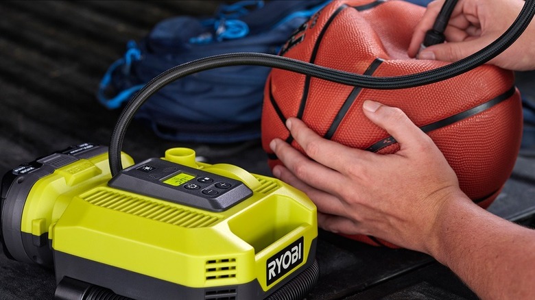 person pumping basketball with inflator