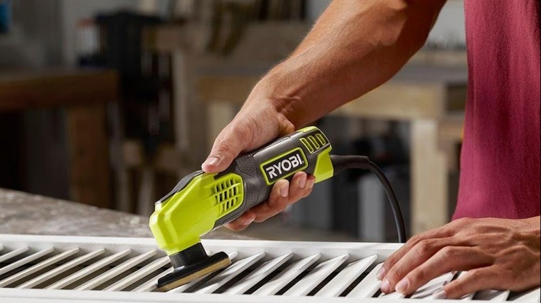 A person using a Ryobi sander on shutters