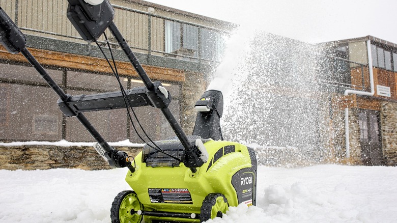 A person pushing a Ryobi brushless snow thrower