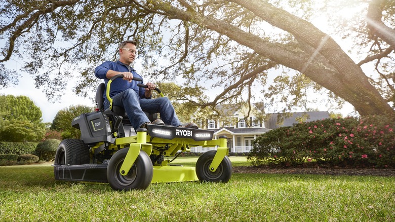 A man riding a Ryobi zero turn electric lawn mower