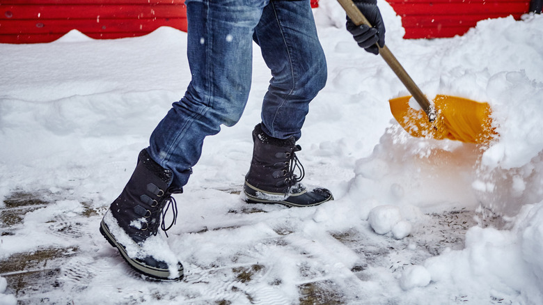 Person shoveling snow from pavers