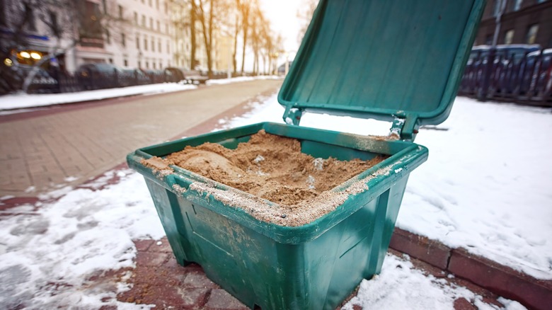 Sand container on snowy pavement