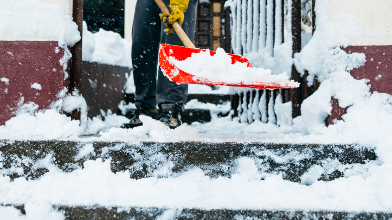 red shovel clearing snow off steps