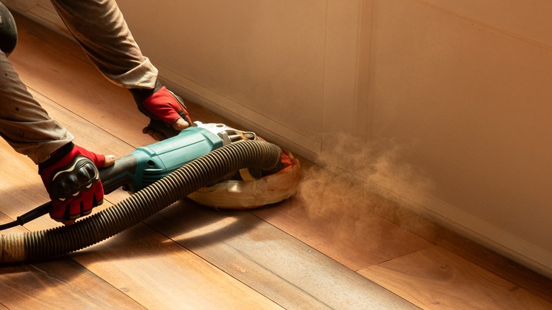 person using sander on hardwood floors