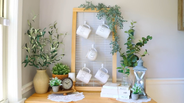 A DIY cooling rack mug holder leaning against the wall, surrounded by greenery, and decorative pieces.