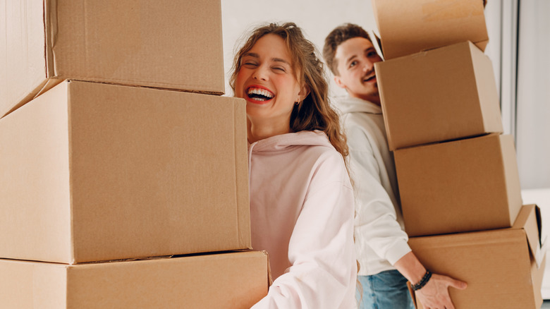 Two people happily carrying cardboard boxes