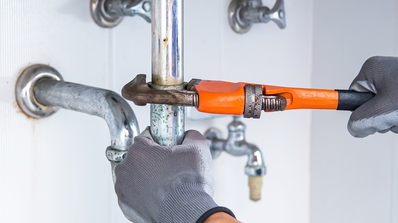 Plumber using wrench on pipe