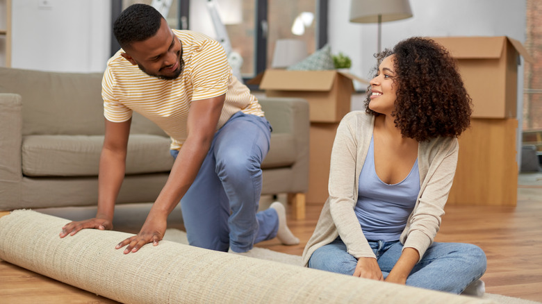 couple rolling out area rug