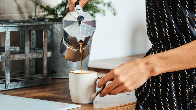 Person pouring a cup of coffee from a French press