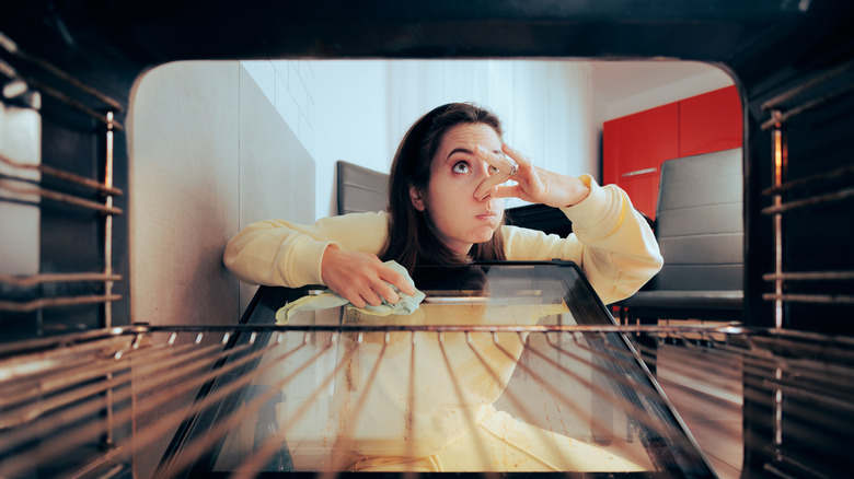 Woman cleans inside of oven door