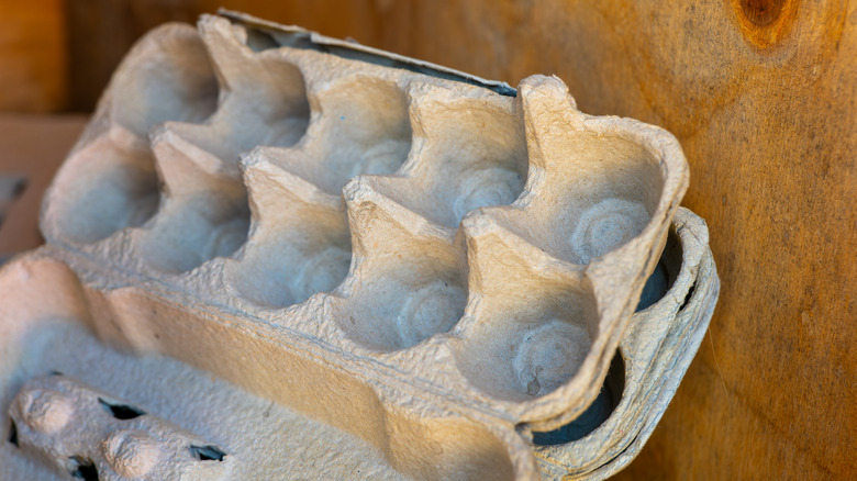 A stack of empty cardboard egg cartons sitting on a wooden surface