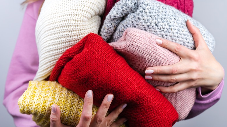 Woman holding sweaters