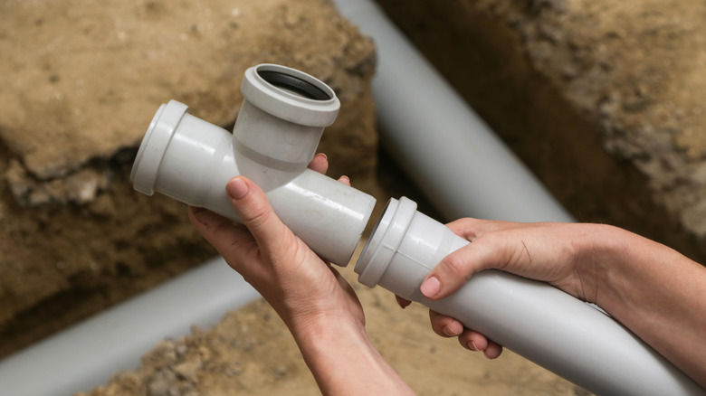 Hands fitting two PVC pipes together